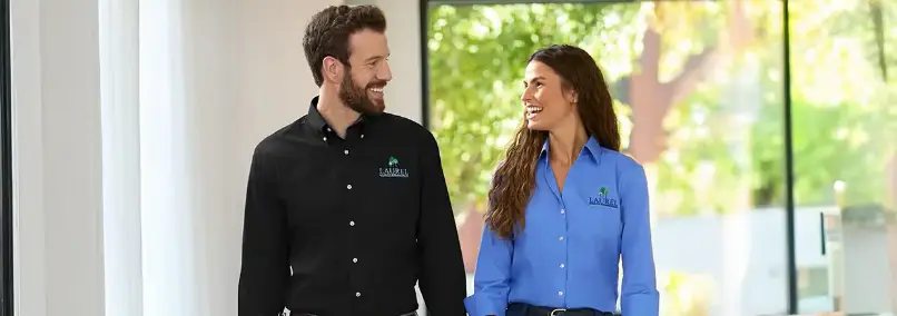 Man and woman smiling while wearing black and blue company uniform shirts